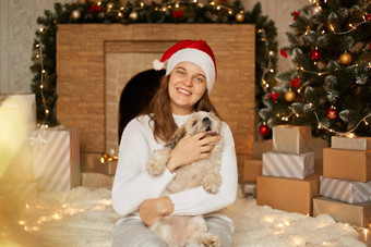 快乐家庭红色的他白色休闲毛衣狗坐着圣诞节树现在盒子壁炉快乐的女孩宠物小狗咬主人的手指