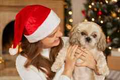 快乐女孩圣诞老人他拥抱可爱的狗背景美丽的圣诞节树灯节日房间温暖的假期大气时刻北京人的老板生活房间