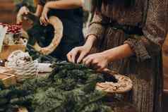 女人使圣诞节花环创建圣诞节花环云杉分支机构纸板框架