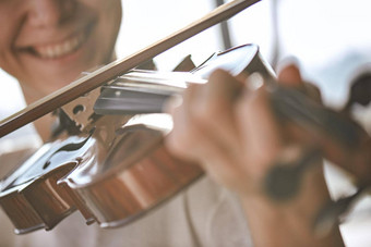 享受经典音乐关闭视图微笑小提琴家玩经典音乐棕色（的）木小提琴