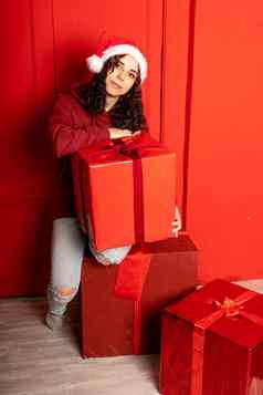 年轻的有吸引力的女人圣诞老人老人他坐在礼物红色的墙笑脸女坐着大盒子礼物概念假期礼物好情绪