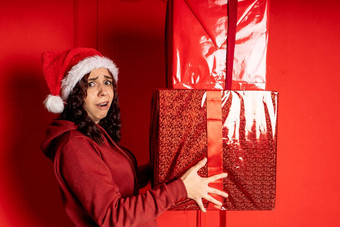 年轻的女人圣诞老人老人他持有重大礼物站红色的墙疲惫女圣诞节他盒子礼物概念假期礼物