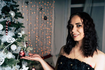 肖像迷人的浅黑肤色的女人黑色的衣服圣诞节树年轻的有吸引力的女人摆姿势松柏科的树装饰装饰概念圣诞节庆祝活动首页
