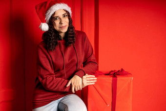 年轻的有吸引力的女人圣诞老人老人他坐在礼物红色的<strong>墙笑脸</strong>女坐着大盒子礼物概念假期礼物好情绪