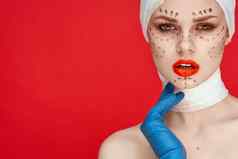 女人摆姿势蓝色的手套红色的嘴唇手术面部复兴孤立的背景
