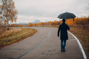 年轻的男人。黑色的外套走雨伞