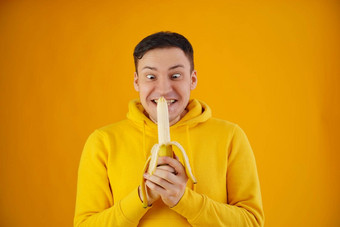 肖像年轻的男人。香蕉黄色的背景有趣的的家伙黄色的连帽衫摆姿势搭配的水果