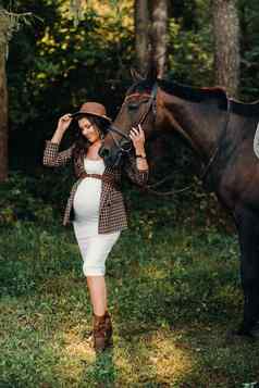 怀孕了女孩大肚子他马森林自然时尚的女孩白色衣服棕色（的）夹克