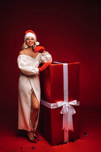 肖像微笑女孩白色衣服圣诞老人他巨大的圣诞节礼物红色的背景