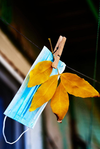 蓝色的医疗面具挂起绳子分支棕色（的）叶子秋天面具模式概念