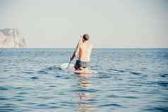 一边视图图片男人。游泳放松董事会运动型男人。海站桨董事会概念活跃的健康的生活和谐自然
