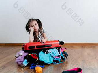 伤心女孩靠红色的手提箱关闭大数量的事情开放边界女孩假期
