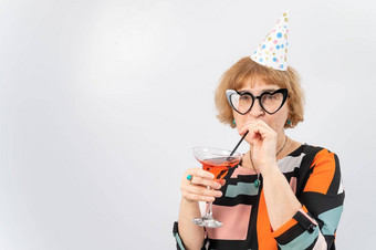肖像微笑上了年纪的女人节日帽眼镜心喝鸡尾酒白色背景