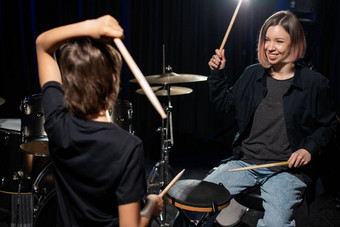 年轻的高加索人女人教男孩玩鼓工作室黑色的背景<strong>音乐学校</strong>学生