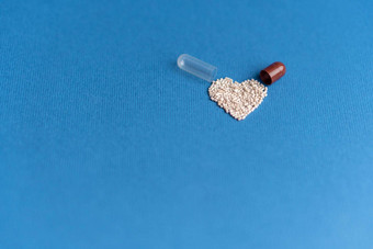 颗粒倒心形的胶囊经典蓝色的背景心形状的药物心象征画药片