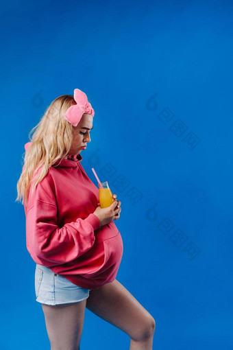 怀孕了女孩粉红色的衣服瓶汁蓝色的背景