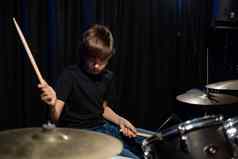 男孩学习玩鼓工作室黑色的背景音乐学校学生