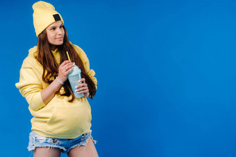 怀孕了女孩黄色的衣服玻璃汁蓝色的背景