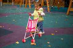 可爱的蹒跚学步的孩子携带婴儿巡回演出的演员走秋天公园