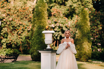 美丽的新娘豪华的婚礼衣服持有玫瑰绿色植物绿色自然背景肖像快乐新娘白色衣服微笑背景公园
