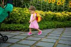 可爱的婴儿女孩粉红色的衣服婴儿背包走路公园