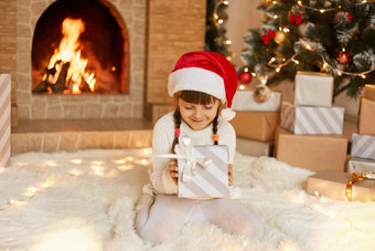 可爱的孩子红色的节日他圣诞节礼物盒子摆姿势首页坐着地板上软地毯壁炉圣诞节树迷人的女孩辫子持有礼物盒子