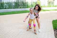 高加索人女人教女儿滑冰辊溜冰鞋
