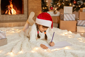 快乐女孩红色的圣诞节他写作信圣诞老人老人画图片女孩子穿白色毛衣温暖的袜子孩子摆姿势节日生活房间壁炉
