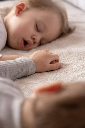 童年睡眠放松家庭生活方式概念年轻的孩子们年穿着白色米色紧身衣裤睡眠米色白色床上午餐持有手前视图