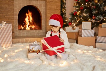 圣诞节孩子开放现在圣诞节树快乐婴儿女孩一年礼物盒子坐着地板上惊讶面部表达式惊讶惊喜