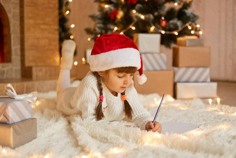 可爱的孩子女孩写作信圣诞老人首页礼物盒子说谎地板上软地毯孩子辫子画图片现在提出了圣诞节树