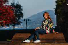 快乐女孩坐在板凳上阳光明媚的秋天日落小镇奥地利女孩提出了小镇背景奥地利阿尔卑斯山脉欧洲维尔登rthersee