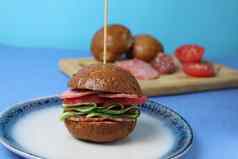 三明治汉堡荞麦棕色（的）好蔬菜块西红柿黄瓜蓝色的板蓝色的背景成分使汉堡蔬菜香肠他