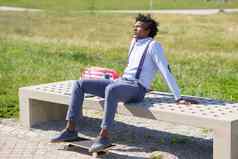 黑色的男人。非洲式发型头发采取咖啡打破坐着公园板凳上
