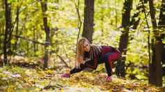 女人健身练习户外女伸展运动秋天森林苗条的女孩锻炼下蹲