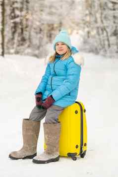 女孩冬天感觉靴子坐在手提箱冷淡的雪一天