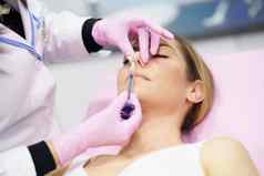 医生执行鼻整形术注射透明质酸酸鼻子病人