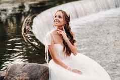优雅的新娘白色衣服手套只脚坐着瀑布公园享受自然模型婚礼衣服手套自然公园白俄罗斯