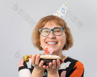 肖像微笑上了年纪的女人节日帽持有蛋糕蜡烛形式数量周年纪念日