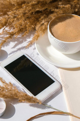 彭巴斯草原草白色杯咖啡移动电话黑色的屏幕检查社会媒体喝卡布奇诺咖啡早餐早....首页平躺壁纸美学