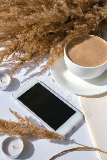 彭巴斯草原草白色杯咖啡移动电话黑色的屏幕检查社会媒体喝卡布奇诺咖啡早餐早....首页平躺壁纸美学