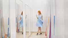 年轻的女人蓝色的衣服镜子拟合房间商店