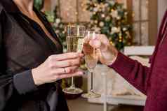 关闭夫妇手持有眼镜香槟圣诞节树灯夫妇庆祝圣诞节冬天假期首页运气快乐