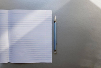 开放学校笔记本笔灰色的桌子上太阳射线窗口空白白色表笔记本写作教育概念复制空间视图平躺