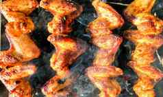 美味的多汁的烤鸡翅膀在户外烟烧烤鸡烹饪过程