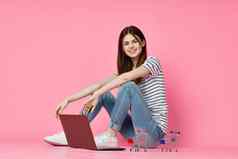 女人移动PC坐着地板上技术互联网购物粉红色的背景