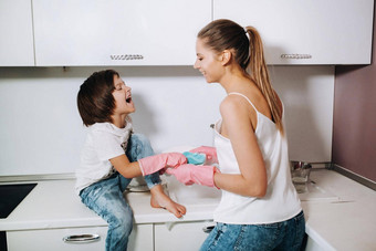 家庭主妇妈妈粉红色的手套洗菜儿子手水槽洗涤剂女孩白色孩子投清洗房子洗菜自制的粉红色的手套孩子投洗菜微笑