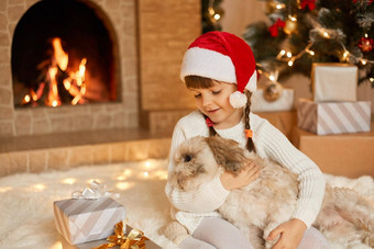 女孩狗一年的夏娃坐着地板上壁炉北京人的礼物快乐穿白色套衫红色的圣诞老人老人他孩子小狗爱