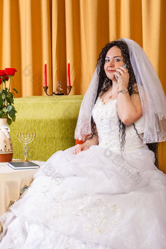 犹太人新娘白色婚礼衣服面纱坐在表格花说话电话婚礼彩棚仪式