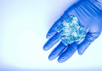 医生持有药物药片药片ω维生素胶囊鱼石油手蓝色的手套药物结合治疗疾病胶囊研究者的手蓝色的手套
